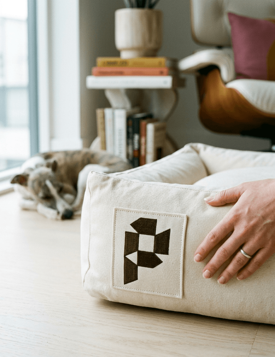Embroidered patch on a canvas dog bed in a Scandinavian living room.